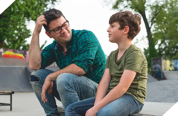 A male care or social worker at a skate park with a child client